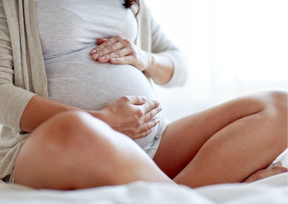 Kobieta w zaawansowanej ciąży trzyma się za brzuch, ponieważ martwi sie o gestozę w ciąży